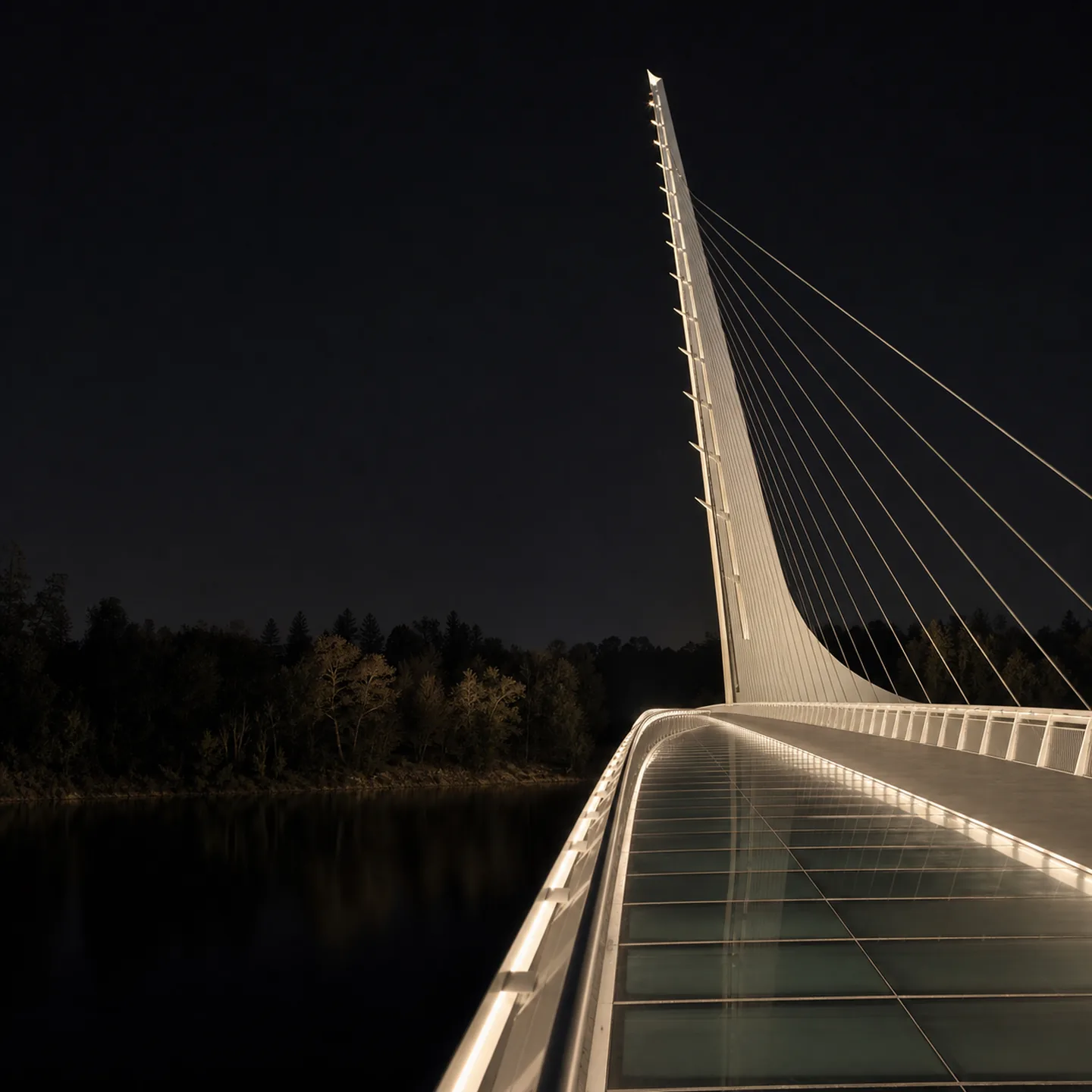 The glass deck and leaning pylon of Redding's Sundial Bridge glow above the Sacramento River at blue hour.